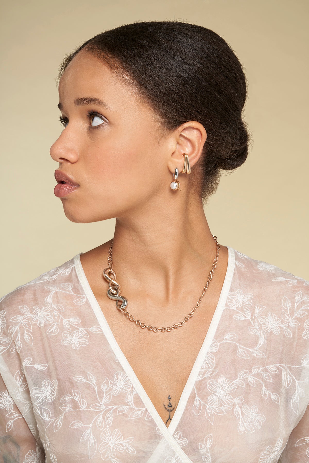 Portrait of woman in white top wearing necklace with silver infinity lock charm and gold infinity lock charm