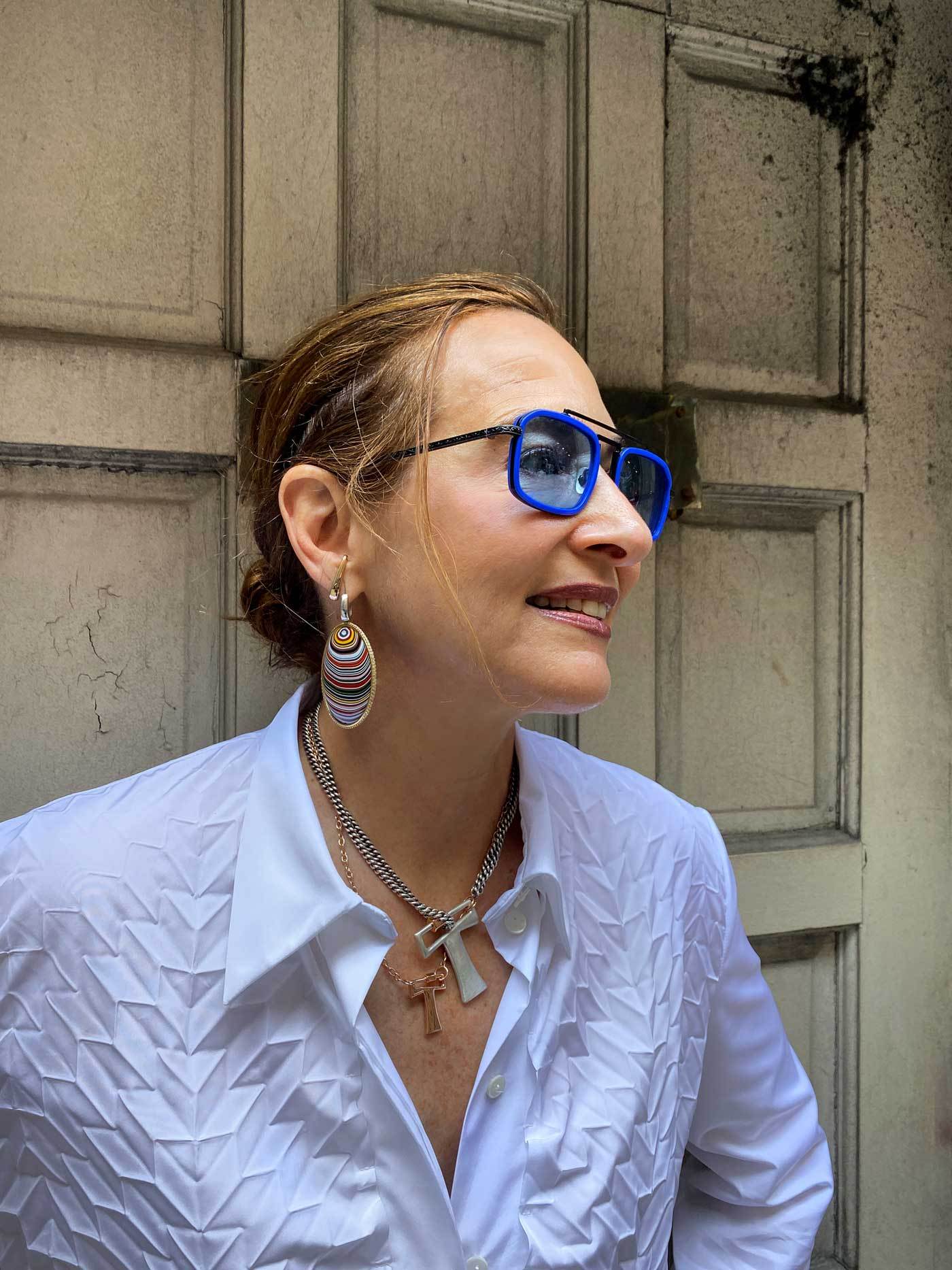 Portrait of woman wearing blue sunglasses and two necklaces with T locks
