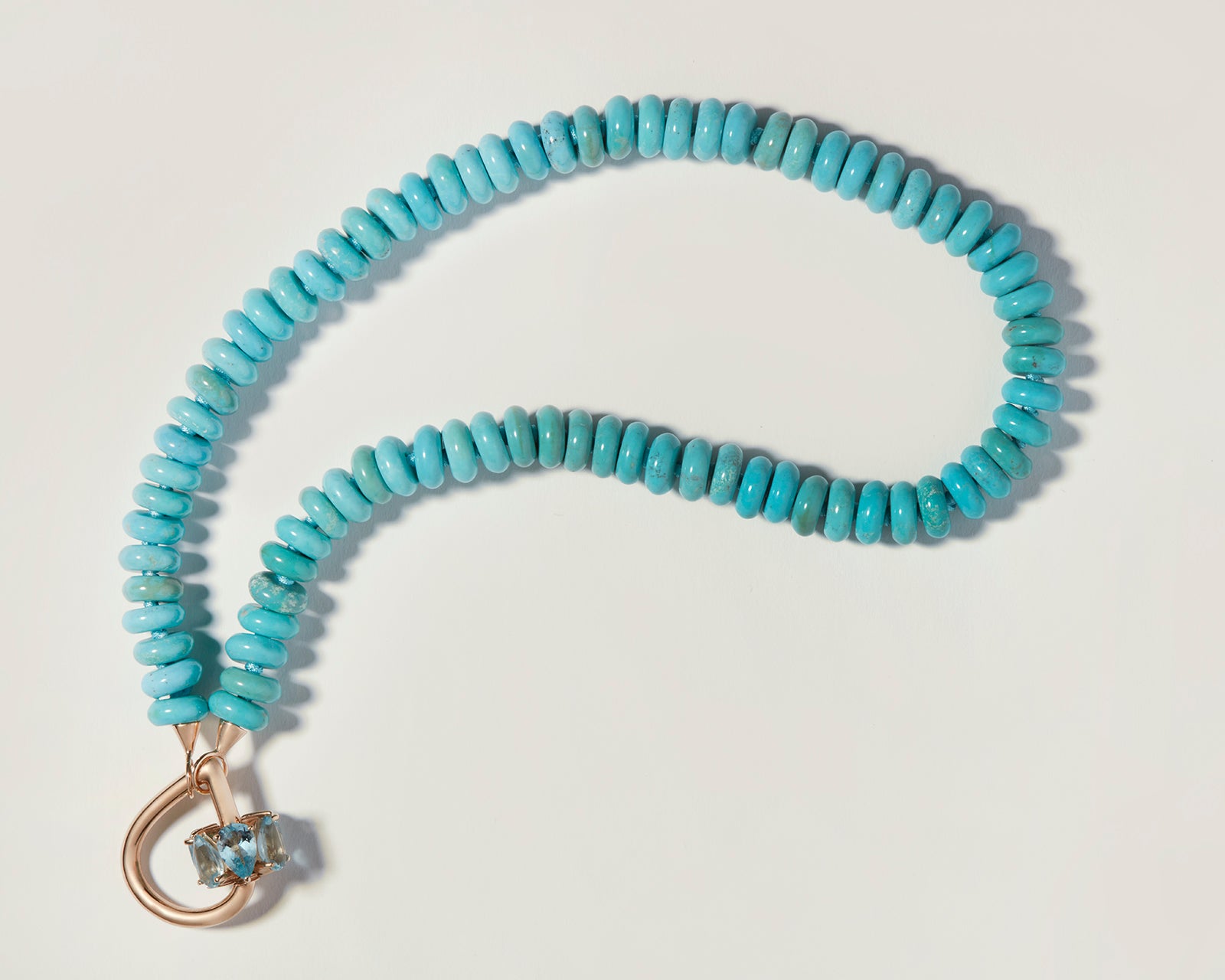 Gold droplock charm with blue gemstones attached to turquoise beaded necklace