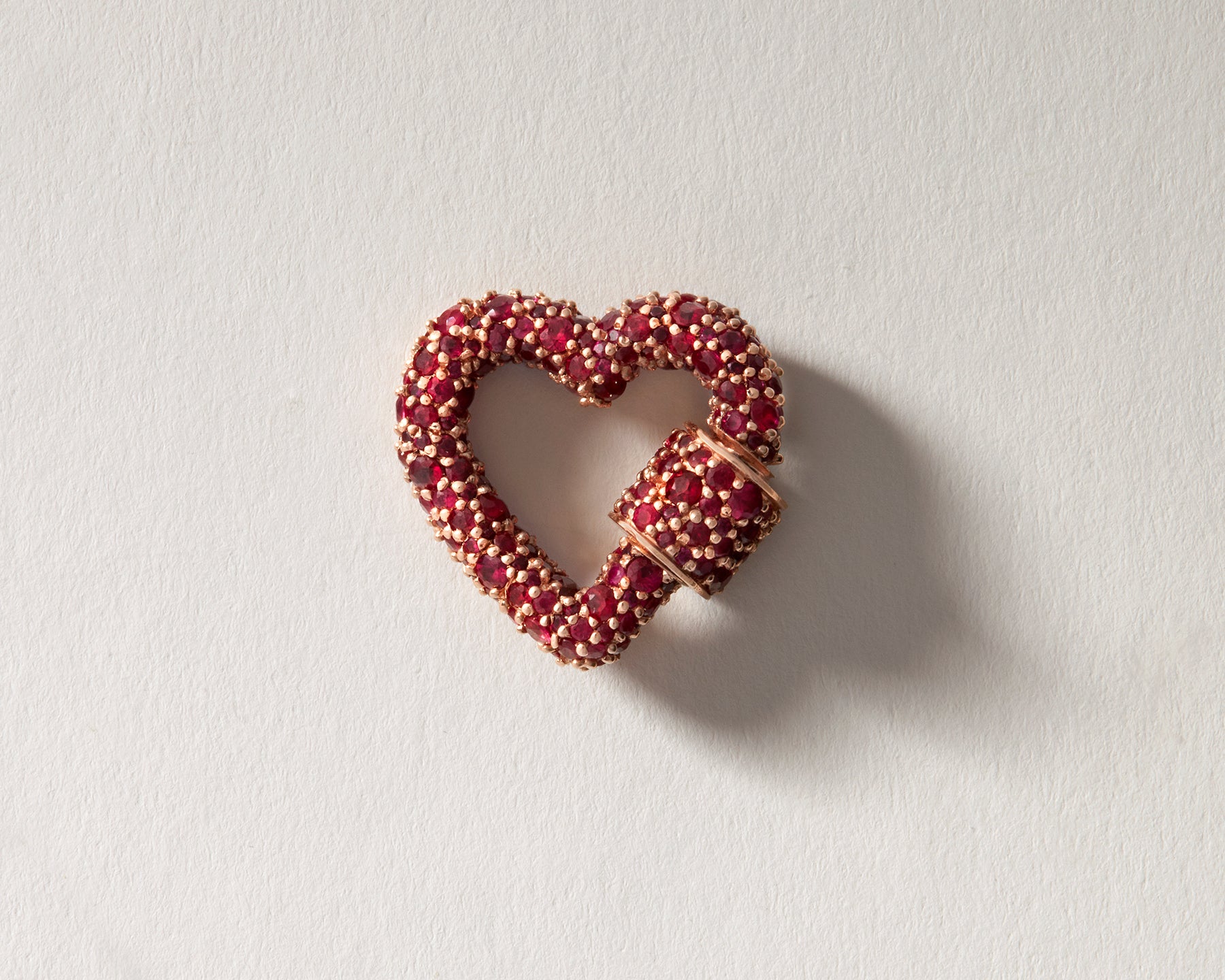 Rose gold ruby heart pendant charm against cream backdrop
