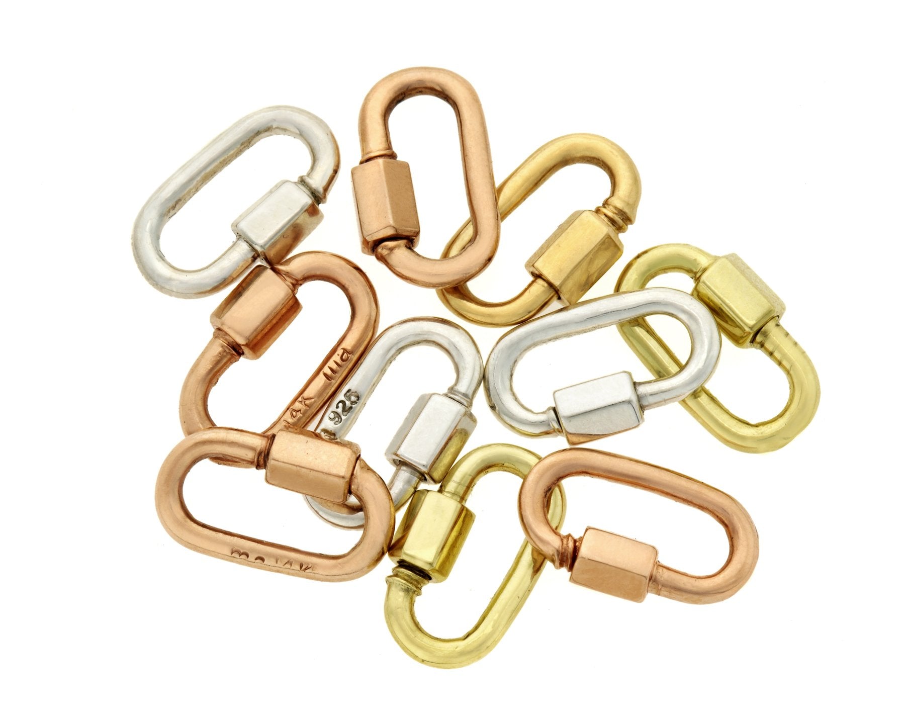 Small pile of Marla Aaron babylocks in different metals against white backdrop