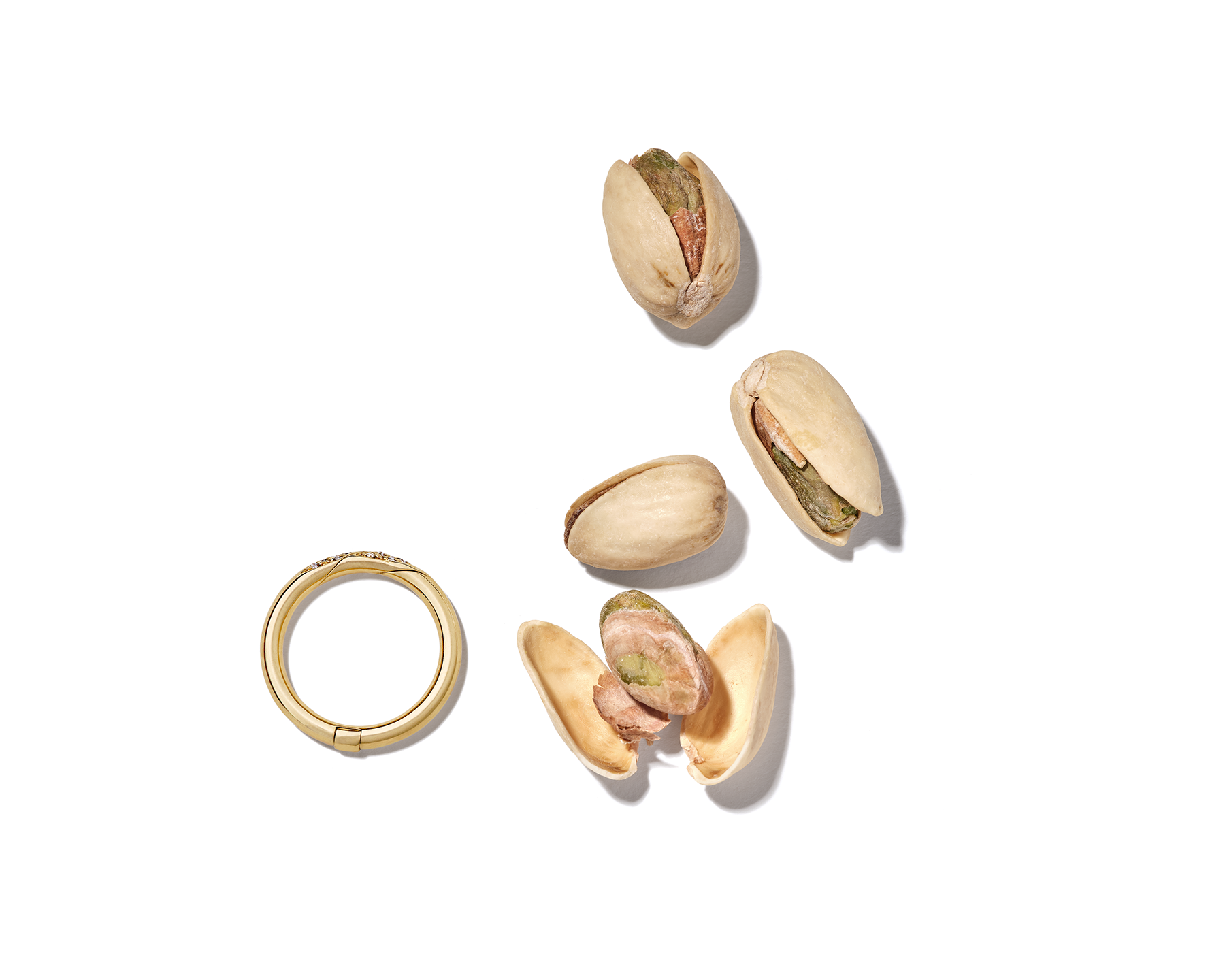 Gold ring alongside small pile of pistachios