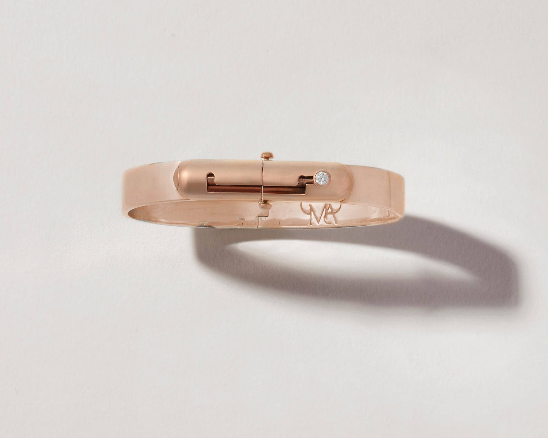 Overhead shot of rose gold bracelet with clasp against white backdrop