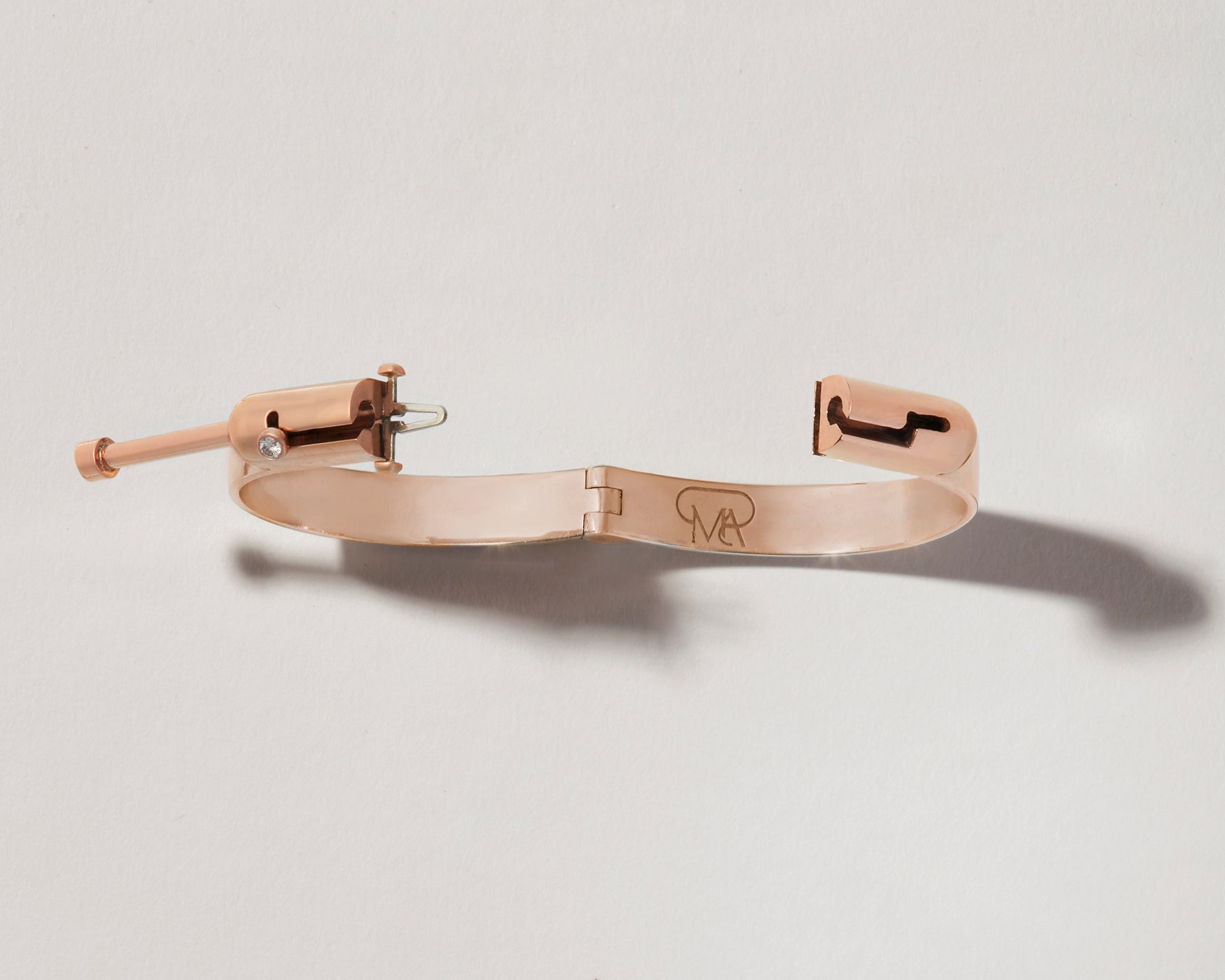 Overhead shot of rose gold bracelet with clasp open against white backdrop