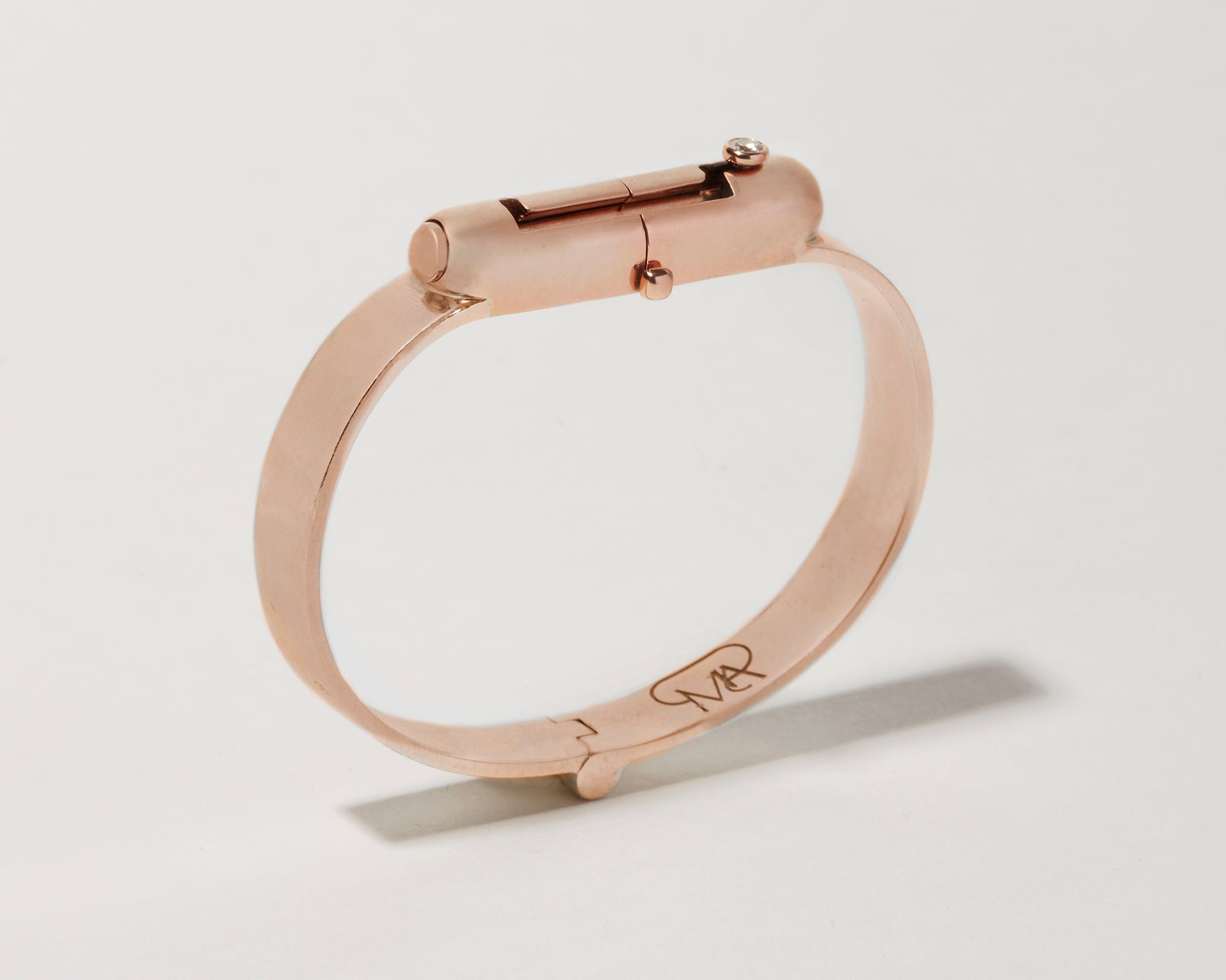 Angled front shot of rose gold clasp bracelet against white backdrop
