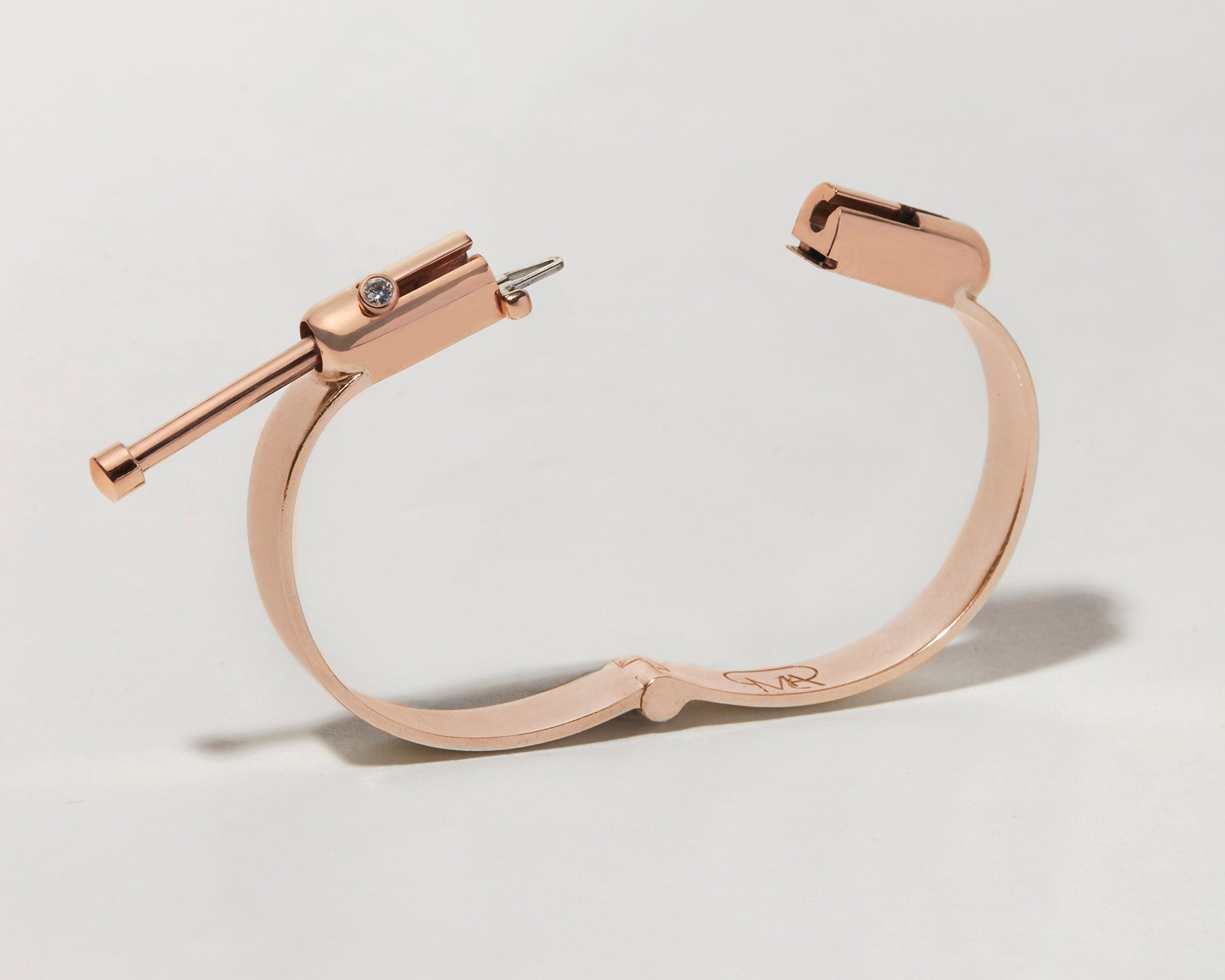 Angled front shot of rose gold clasp bracelet with clasp open against white backdrop
