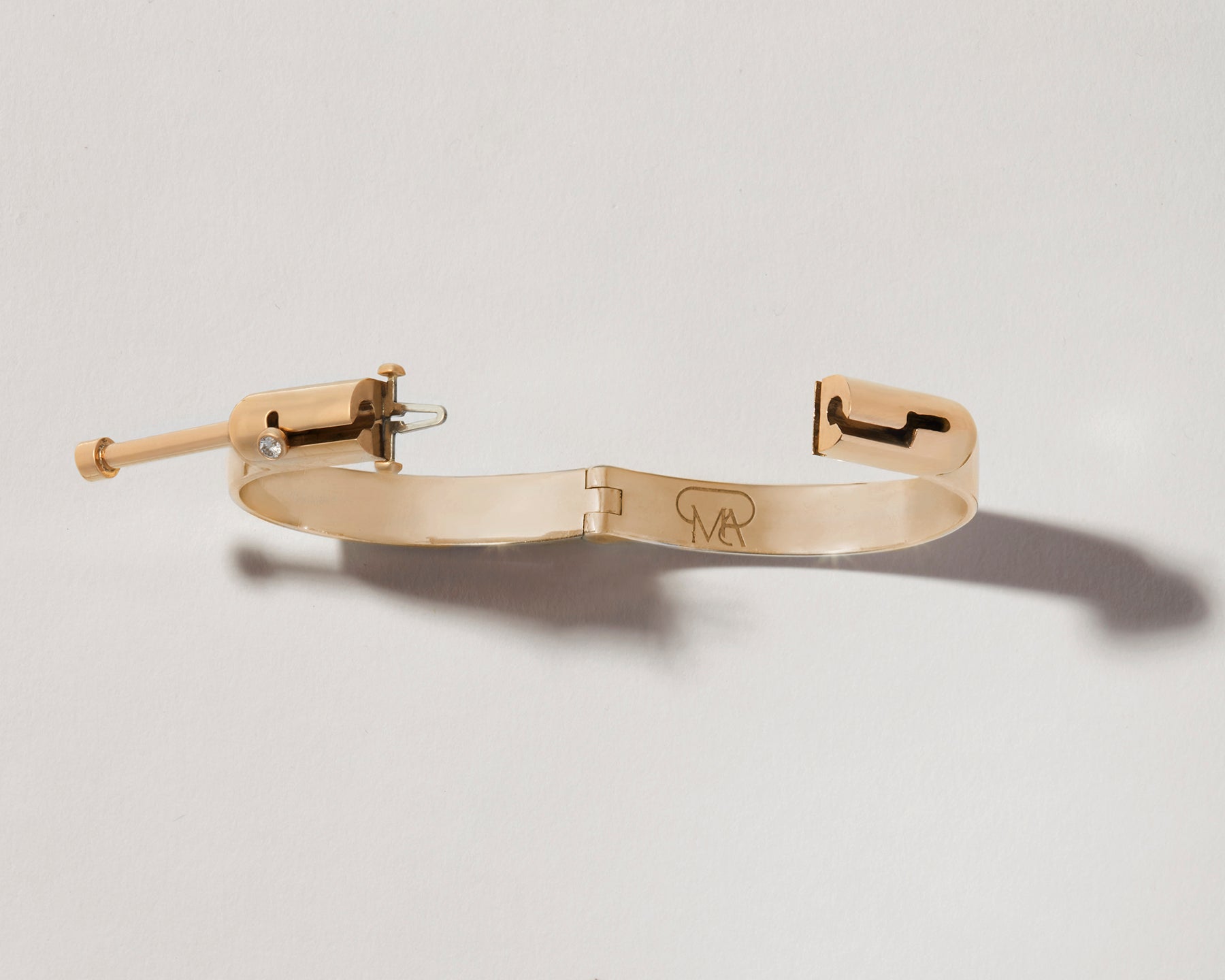 Overhead shot of Zephyr gold clasp bracelet with clasp open against white backdrop