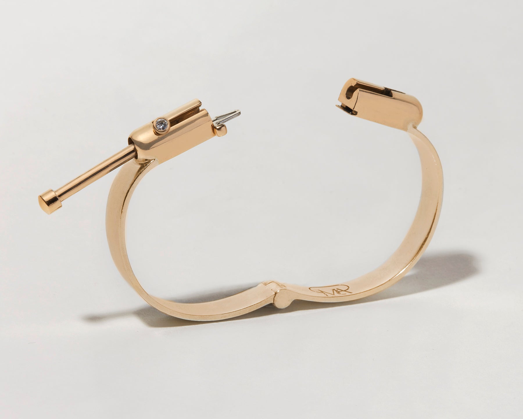 Angled front shot of gold clasp bracelet with clasp open against white backdrop